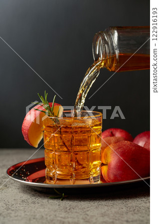Apple juice is poured from a bottle into a glass. Apple juice is poured from a bottle into a glass. 122916193