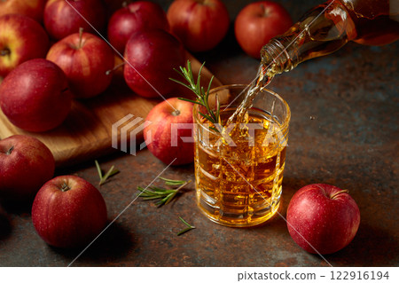 Apple cider is poured from a bottle into a glass. Apple cider is poured from a bottle into a glass. 122916194