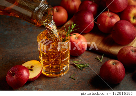 Apple juice is poured from a bottle into a glass. Apple juice is poured from a bottle into a glass. 122916195