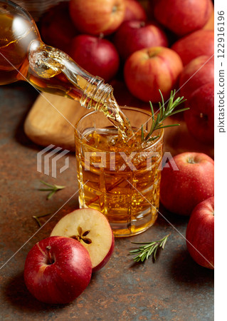 Apple cider is poured from a bottle into a glass. Apple cider is poured from a bottle into a glass. 122916196