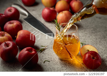 Apple cider is poured from a bottle into a glass. 122916197