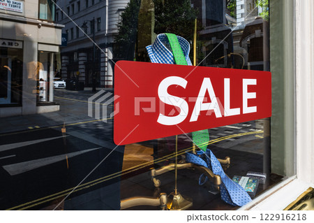 Red Sale Sign on a Fashion Boutique Window with City Reflections in the Glass 122916218