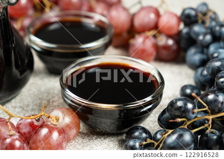 Balsamic vinegar poured into a glass sauce dish among the grapes 122916528