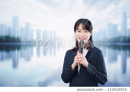 A young woman giving a speech using a microphone on a street corner 122916910