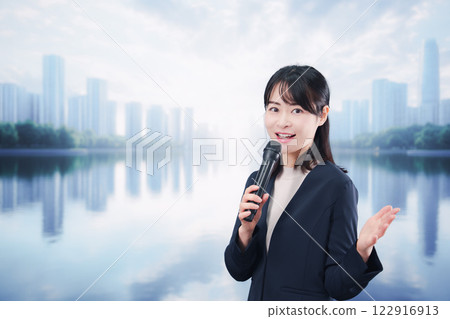 A young woman giving a speech using a microphone on a street corner 122916913