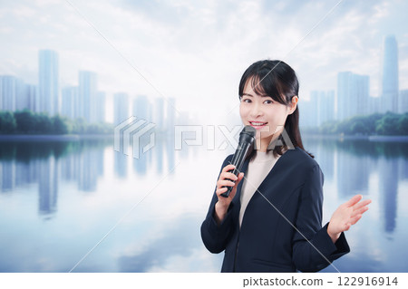 A young woman giving a speech using a microphone on a street corner 122916914