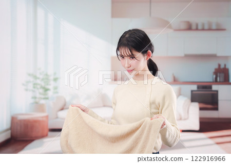 Young woman folding laundry at home 122916966