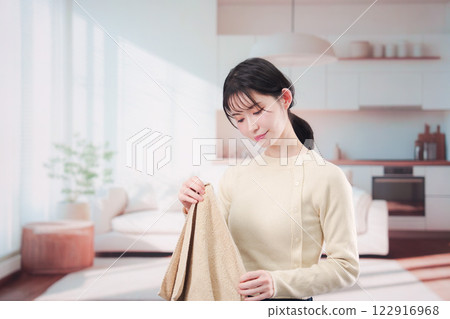 Young woman folding laundry at home 122916968