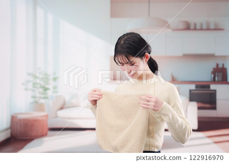 Young woman folding laundry at home 122916970