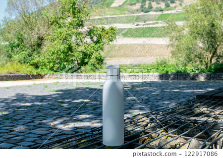 White thermo stainless bottle with refreshing water in the park. 122917086