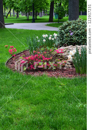 A well-kept garden with a green lawn border and a flower bed. Red Flower Garden Border 122917231