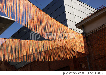 Many red ribbons flutter in the wind on urban background. Festival in the country. The concept of a festive decoration. High quality photo 122917812