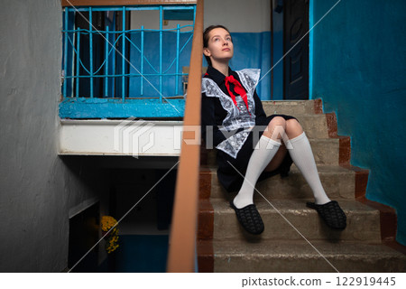 A young girl in a Soviet school uniform is sitting on the stairs in the entrance.the style of the Soviet Union A young girl in a Soviet school uniform is sitting on the stairs in the entrance.the style of the Soviet Union 122919445