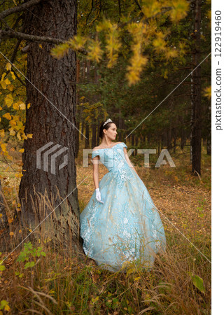 Beautiful brunette girl in a blue ball gown in a colorful forest Beautiful brunette girl in a blue ball gown in a colorful forest 122919460