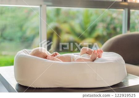 A newborn baby lies peacefully in their cozy sleep cocoon, gazing out of the window. A serene moment of curiosity and calm, symbolizing the early stages of life, peaceful reflection, and a connection A newborn baby lies peacefully in their cozy sleep cocoon, gazing out of the window. A serene moment of curiosity and calm, symbolizing the early stages of life, peaceful reflection, and a connection 122919525