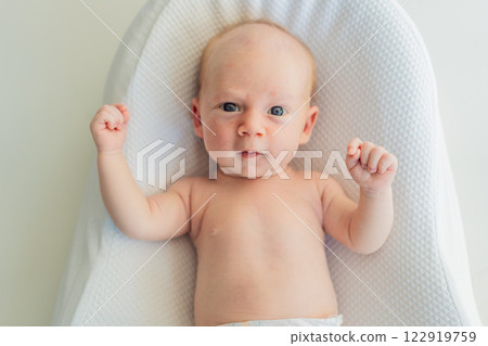 Adorable baby lying safely in a cozy infant cocoon. Comfortable and protective design for newborn care. Parenting, safety, and baby comfort concept Adorable baby lying safely in a cozy infant cocoon. Comfortable and protective design for newborn care. Parenting, safety, and baby comfort concept 122919759