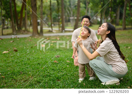 Happy family having fun blowing soap bubbles in park Happy family having fun blowing soap bubbles in park 122920203