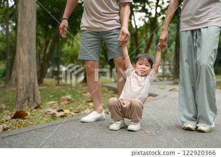 Happy family walking together along a park path, holding hands Happy family walking together along a park path, holding hands 122920366