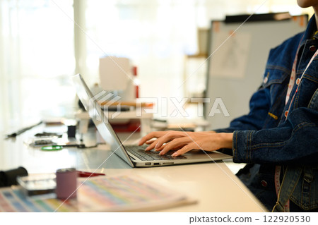 Close up of designer hands typing on laptop in a creative workspace Close up of designer hands typing on laptop in a creative workspace 122920530