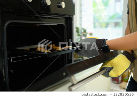 Man putting a tray full of chocolate chip cookies into a preheated oven Man putting a tray full of chocolate chip cookies into a preheated oven 122920536