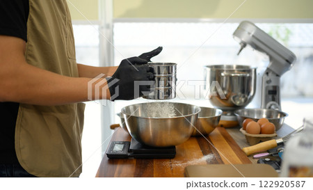 Baker sifting flour while preparing ingredients for cookie dough Baker sifting flour while preparing ingredients for cookie dough 122920587