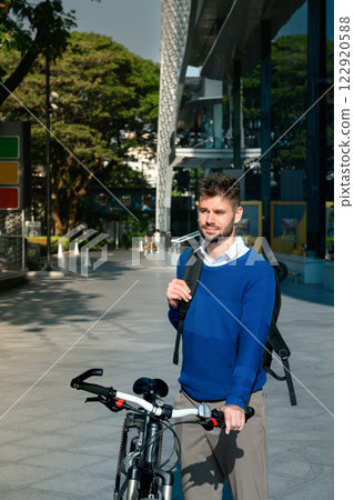 Young caucasian man standing with his bicycle in a modern city. Sustainable Transportation concept Young caucasian man standing with his bicycle in a modern city. Sustainable Transportation concept 122920588