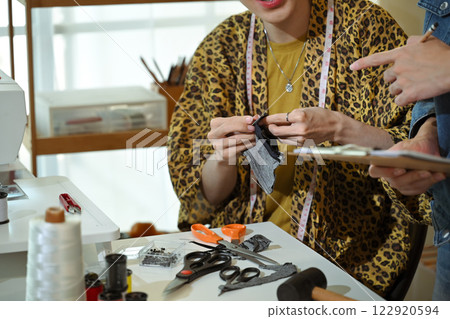 Tailor or designer stitching fabric while working on project with partner Tailor or designer stitching fabric while working on project with partner 122920594