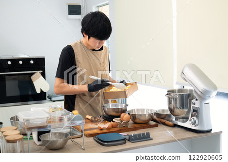 Young baker wearing gloves preparing ingredients for cookie dough Young baker wearing gloves preparing ingredients for cookie dough 122920605