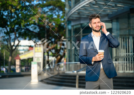 Bearded businessman talking on mobile phone outside office building Bearded businessman talking on mobile phone outside office building 122920620