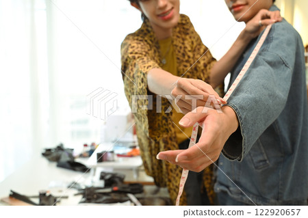 Close up of tailor measuring sleeve length for a custom garment Close up of tailor measuring sleeve length for a custom garment 122920657