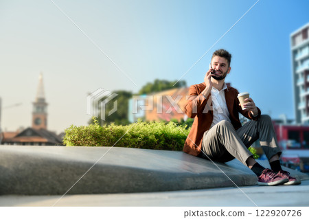 Businessman with a coffee cup talking on mobile phone in the financial district Businessman with a coffee cup talking on mobile phone in the financial district 122920726
