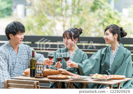 Men and women, colleagues and friends in yukata toasting on a balcony or wooden deck 122920929