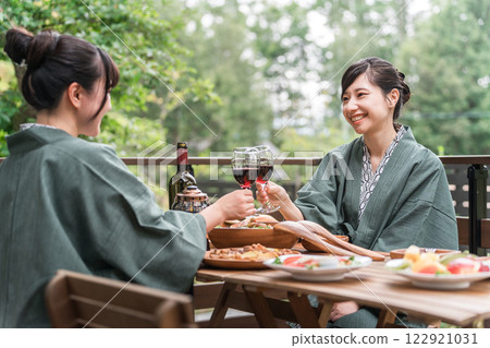 Young Asian woman on a girls trip to a Japanese inn/hot spring inn eating on a balcony/wooden deck (travel/travel) 122921031