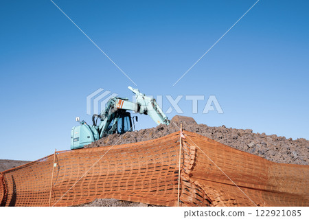 Earthwork embankment and excavator in cool colors 122921085