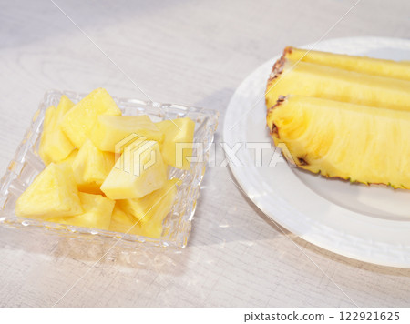 Piece of pineapple in glass bowl on white wood background. Piece of pineapple in glass bowl on white wood background. 122921625