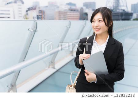 A businesswoman wearing a suit and holding a tablet in an office district 122922238