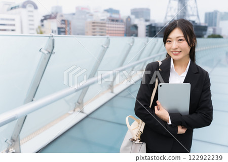 A businesswoman wearing a suit and holding a tablet in an office district 122922239