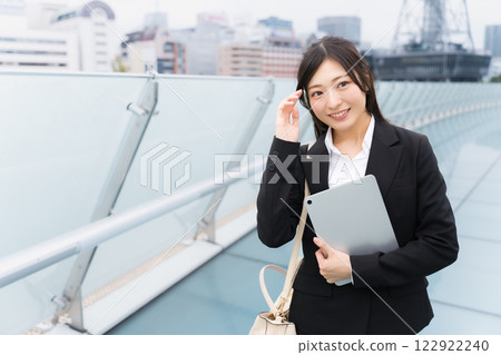 A businesswoman wearing a suit and holding a tablet in an office district A businesswoman wearing a suit and holding a tablet in an office district 122922240