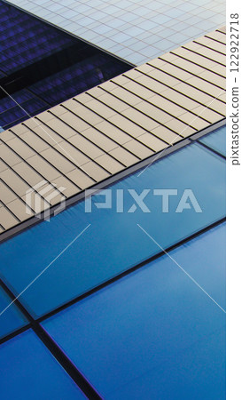 Close-up of a modern building facade featuring alternating blue glass panels and sleek metallic surfaces, emphasizing architectural precision and contemporary design Close-up of a modern building facade featuring alternating blue glass panels and sleek metallic surfaces, emphasizing architectural precision and contemporary design 122922718