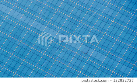 A close-up view of a contemporary building showcasing glass panels reflecting soft clouds and a blue sky, emphasizing symmetry and urban sophistication 122922725