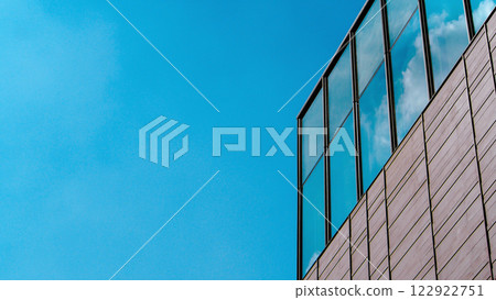 Modern Harmony: A Glass-Framed Building Reflecting Soft Clouds Against a Backdrop of Clear Blue Sky Modern Harmony: A Glass-Framed Building Reflecting Soft Clouds Against a Backdrop of Clear Blue Sky 122922751