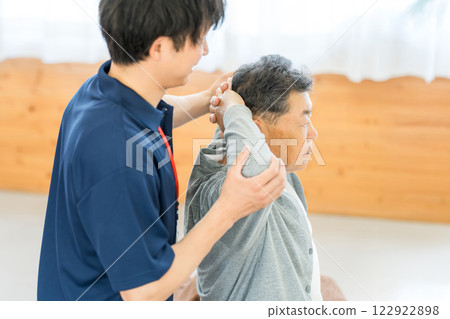 Senior man doing exercises for rehabilitation and male staff including physical therapist and occupational therapist 122922898