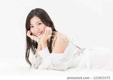 美女圖片：一位年輕女子躺著，臉頰靠在腹部，面帶微笑，看著鏡頭 122923375