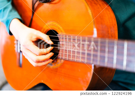 年輕女子在客廳練習吉他，沒有臉 122924196