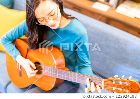 客廳裡彈吉他的年輕女子 122924198