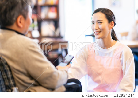 Smiling caregiver from care service and senior man in wheelchair Smiling caregiver from care service and senior man in wheelchair 122924214