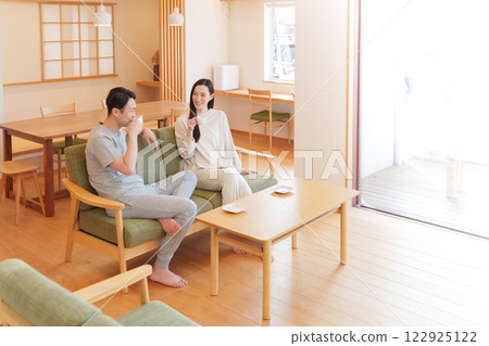 A couple waking up in the morning and drinking coffee in the living room A couple waking up in the morning and drinking coffee in the living room 122925122