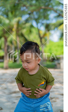 Adorable Little Boy Holding Tummy on Beach Sand Vacation with Palm Trees Adorable Little Boy Holding Tummy on Beach Sand Vacation with Palm Trees 122925885