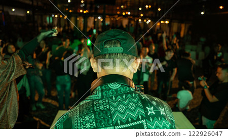 DJ Plays to Energetic Crowd at Outdoor Music Festival Under Bokeh Lights 122926047