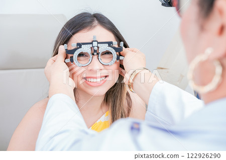 Vision check with optometrist trial frame on patient. Doctor checking vision of patient with trial frame in ophthalmology clinic 122926290